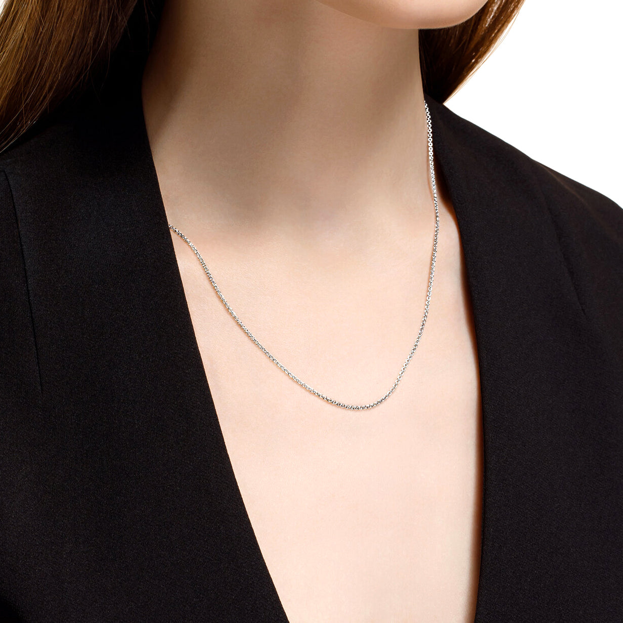 Silver necklace worn by a person against a black background